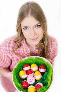 Paskalya yumurtaları taşıyan sepeti tutan güzel, genç bir kadının yüksek açılı görüntüsü.