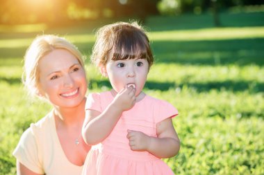 Anne gün batımı parkında şeker yerken küçük kızına bakıyor.