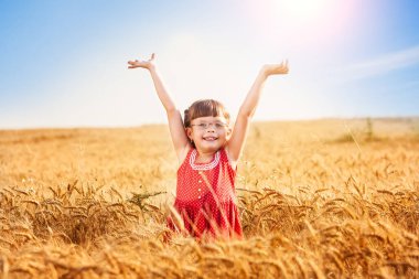 Kollarını buğday tarlasına uzatmış küçük bir kız