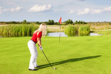 Bayan golfçü, yaz gününde sallanmaya hazır.