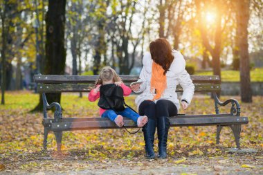 Anne küçük kızına bakıyor. Kadın çantasına bakmaktan nasıl da zevk alıyor.