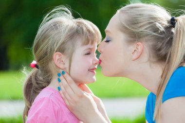 Bir abla kız kardeşini sevgiyle öpüyor.