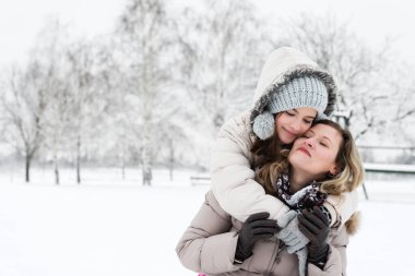 Anne ve kızı kışın açık havada kucaklaşıyorlar.