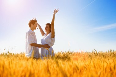 Mutlu genç çift buğday tarlasında eğleniyor, yaz mevsimi