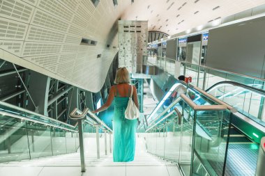 Mavi elbiseli genç bir kadın modern bir alışveriş merkezinde yürüyor..