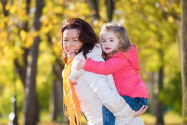Anne ve kızı sonbahar parkında eğleniyor.