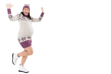 Mutlu, genç hamile bir kadın beyaz bir arka planda kışın dans ediyor..