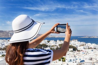 Şapkalı turist kız Santorini 'de fotoğraf çekiyor.