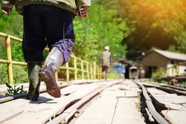 Havza madeninde demiryolu hattından geçen madencilerin arka görüntüsü, hareket bulanıklığı, mercek parıltısı.