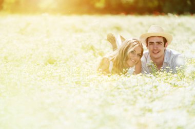Mutlu, genç bir çift oturmuş papatya çayırında eğleniyor.