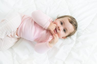 Yatakta uzanmış kameraya bakan tatlı küçük kızın yüksek açılı görüntüsü.