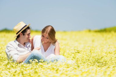 Mutlu, genç bir çift oturmuş papatya çayırında eğleniyor.
