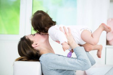 Genç anne sırt üstü uzanıyor ve küçük kızını öpüyor.. 