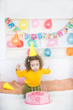 Küçük kız doğum günü pastasında mum üflüyor..