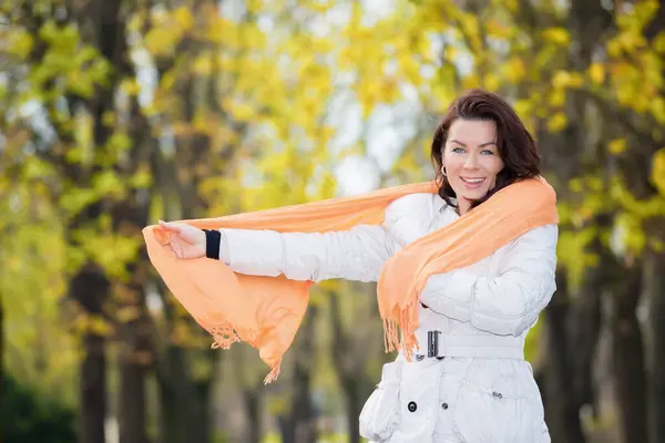 Sonbahar parkında poz veren mutlu kadın.