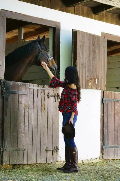 Kovboy kız ahırda atına bakıyor.                             