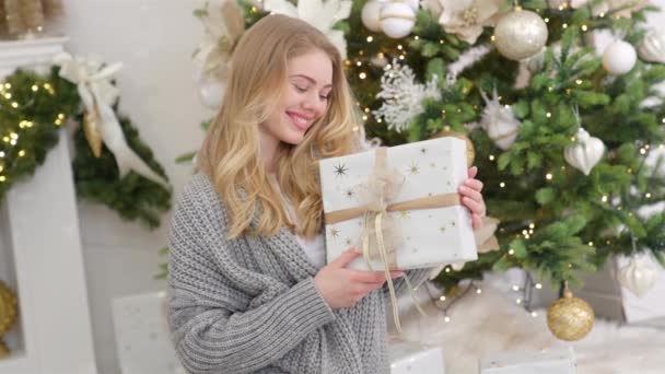 Усміхнена Блондинка Позує Різдвяною Загорнутою Подарунковою Коробкою Поруч Сосновим Деревом — стокове відео