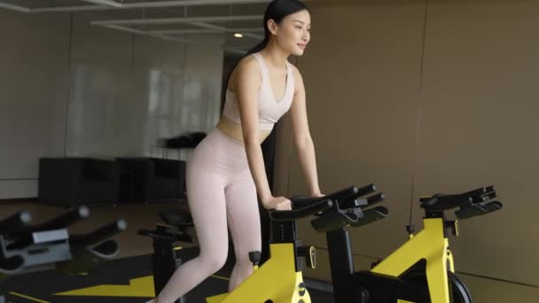 Ung Vältränad Thailändsk Kvinna Sportkläder Som Cyklar Inomhus För Att — Stockvideo