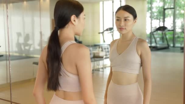 Ung Thailändsk Kvinna Står Ett Gym Tittar Hennes Smala Figurer — Stockvideo