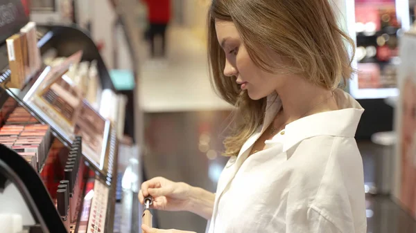 エレガントな若い女性のテストと小売店で化粧品の色合いを選択 — ストック写真