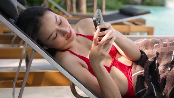 여름을 즐기는 아시아 의자에 그녀의 전화와 즐기다 — 비디오