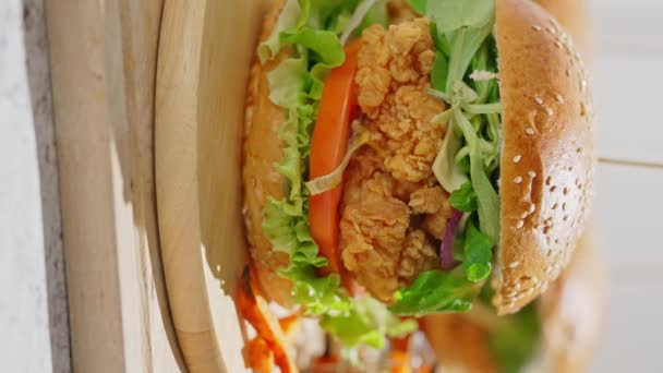 新鲜美味的酥脆鸡肉汉堡包 配上融化的奶酪 西红柿 玉米和酱汁 放在木制盘子里 — 图库视频影像
