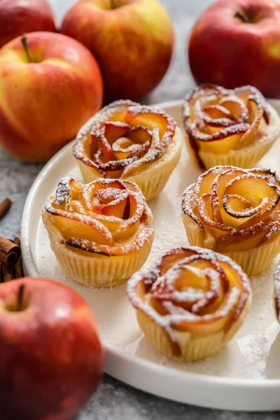 Freshly baked apple roses cakes served on white plate, flat lay. Beautiful dessert concept