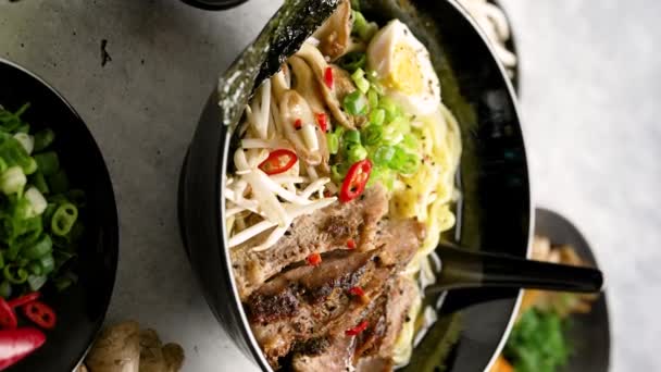 肉スープ アジア麺 スライスした豚肉 ジンジャーをコンクリートの背景にしたおいしい和菓子ラーメン クローズアップ アジアスタイルの食べ物 トップビュー ホットおいしいラーメンスープ — ストック動画