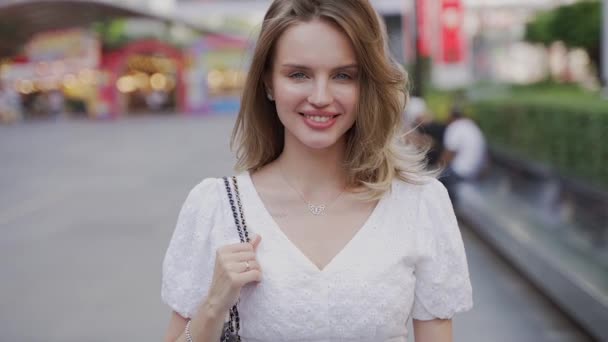 Щаслива Жінка Білій Сукні Йде Вулиці Посміхаючись Насолоджуючись Неквапливою Прогулянкою — стокове відео