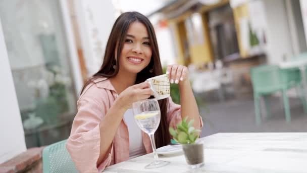 Μια Χαμογελαστή Νεαρή Γυναίκα Κάθεται Ένα Υπαίθριο Τραπεζάκι Καφέ Στην — Αρχείο Βίντεο