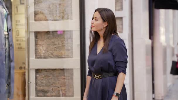 一个穿着时髦衣服的老练女人走在西班牙城市的一家商店的门口 流露出自信和优雅 — 图库视频影像