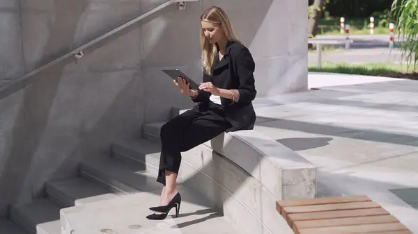 화창한 콘크리트 단계에 그녀의 태블릿에 Engrossed 비즈니스 복장에 스톡 사진