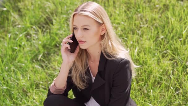 Μια Νεαρή Επαγγελματίας Γυναίκα Μιλάει Κινητό Τηλέφωνο Ένα Χορταριασμένο Τομέα — Αρχείο Βίντεο
