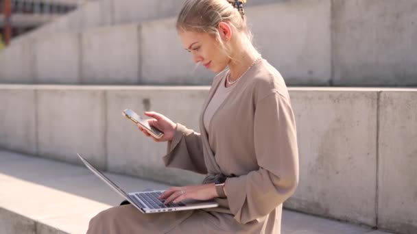 Mujer Profesional Enfocada Utilizando Ordenador Portátil Teléfono Inteligente Simultáneamente Mientras — Vídeo de stock