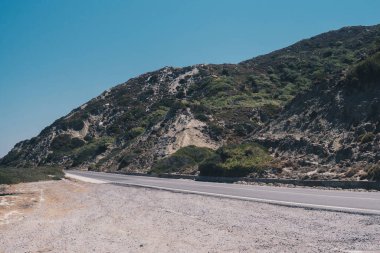 Landscape with asphalt road in front of mountains during sunny day in Greece