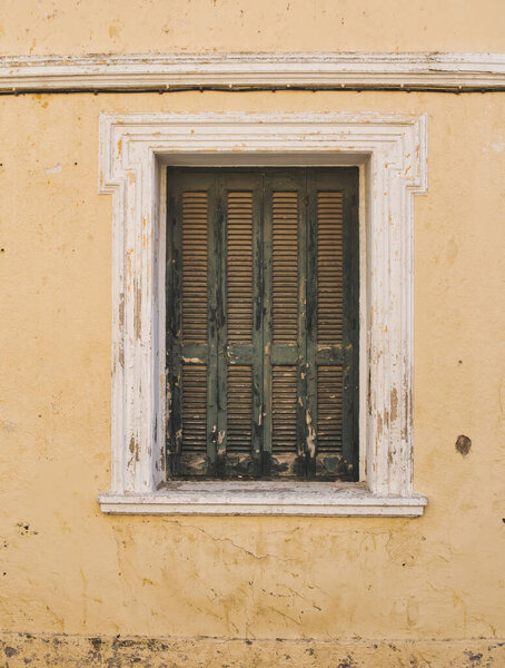 Detail of old window with closed shutter on a facade of an abandoned house in Greece
