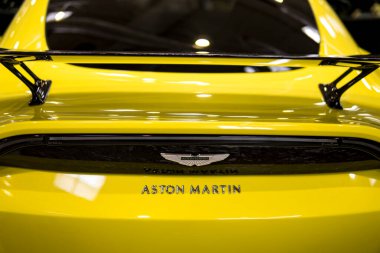 Sarı bir arabanın kaputunda Aston Martin amblemi.