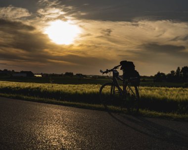 Gün batımında tarlanın önünde duran tek bir bisiklet.