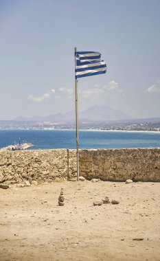 Akdeniz 'in arka planına karşı Rethymno kentindeki Venedik kalesinin duvarları içindeki Yunan bayrağı