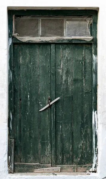 Yeşil ahşap kapılı eski bir binanın beyaz duvarı.