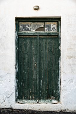 Yeşil ahşap kapılı eski bir binanın beyaz duvarı.