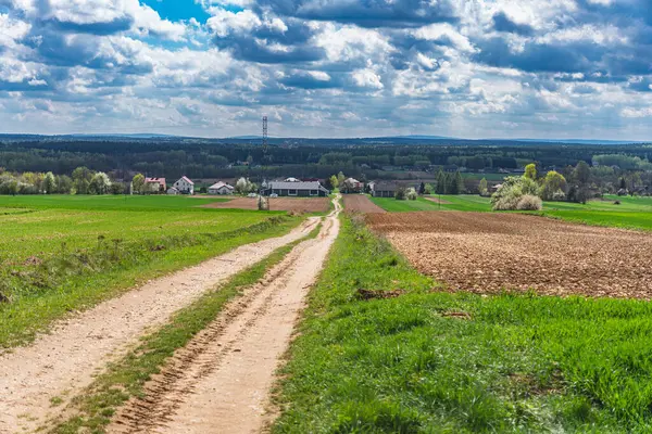 Baharın başında kümülüs bulutlarıyla köy ve tarlaları gösteren manzara