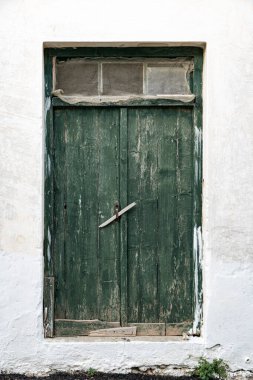 Yeşil ahşap kapılı eski bir binanın beyaz duvarı.