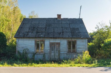 Asfalt yolun kenarında duran terk edilmiş eski bir ev.