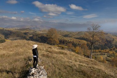 Genç bir kadın gözlerinin önündeki güzel sonbahar manzarasına hayran..