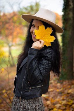 Kameranın önünde yaprak tutan güzel, gülümseyen kadın portresi..