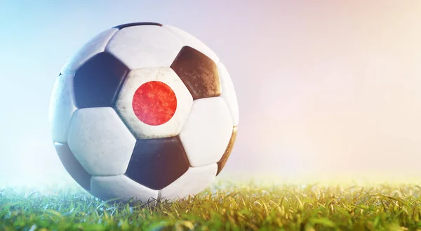 Football soccer ball with flag of Japan on grass. German national team