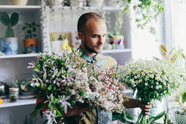 Man with bouquet from fresh flowers in florist shop. Small business and creative work