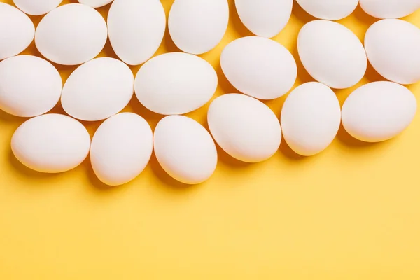 黄色の背景に白い卵 イースター — ストック写真