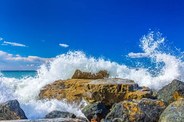 天気の良い青空に岩の上で波がクラッシュし スプラッシュ — ストック写真
